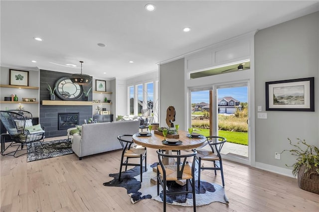 dining area featuring baseboards, light wood-type flooring, a fireplace, and recessed lighting