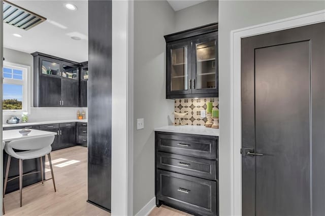 bar featuring light wood finished floors, recessed lighting, visible vents, decorative backsplash, and baseboards