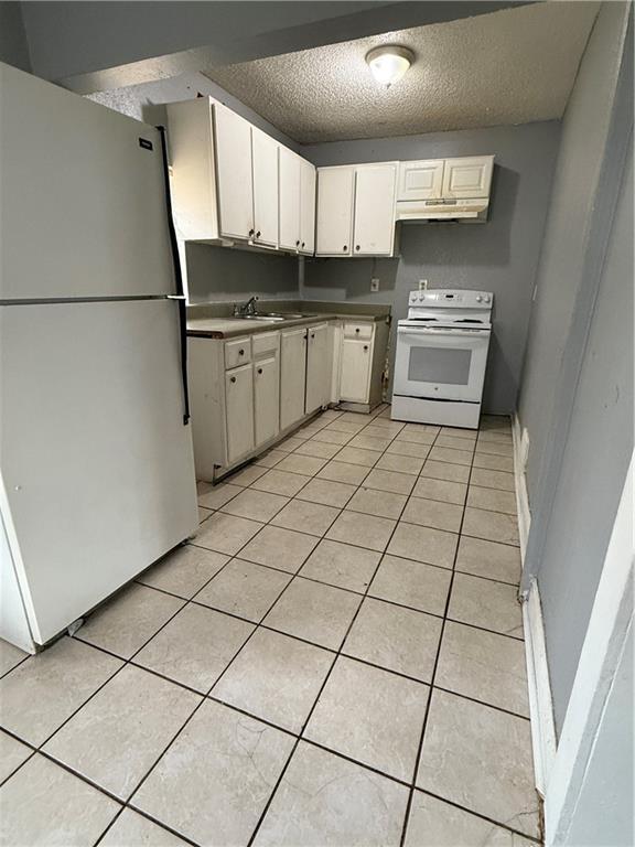 kitchen with freestanding refrigerator, light tile patterned flooring, white electric stove, and under cabinet range hood