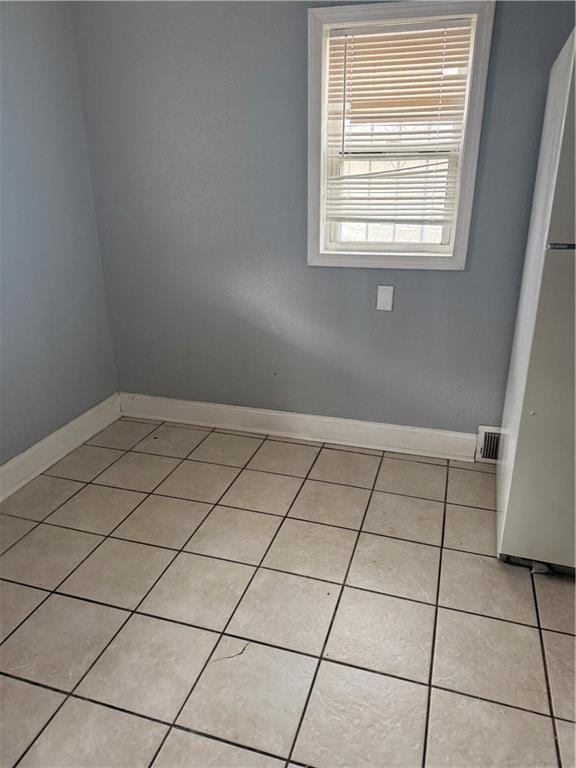 spare room with light tile patterned floors, visible vents, and baseboards