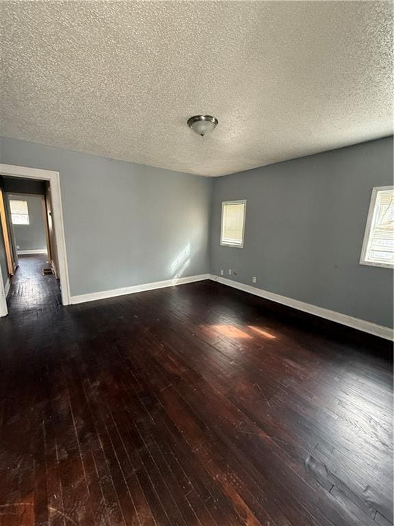 empty room featuring a textured ceiling, baseboards, and hardwood / wood-style floors