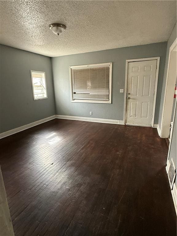 spare room with dark wood-style floors, baseboards, and a textured ceiling