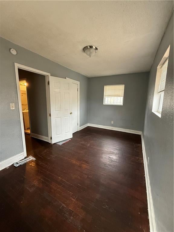 unfurnished bedroom with a textured ceiling, baseboards, and wood finished floors