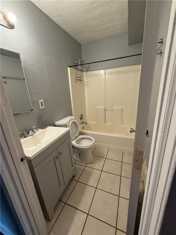 full bath featuring bathing tub / shower combination, a textured wall, a textured ceiling, vanity, and tile patterned flooring