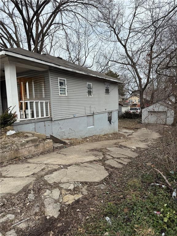 view of side of home featuring a porch and an outdoor structure