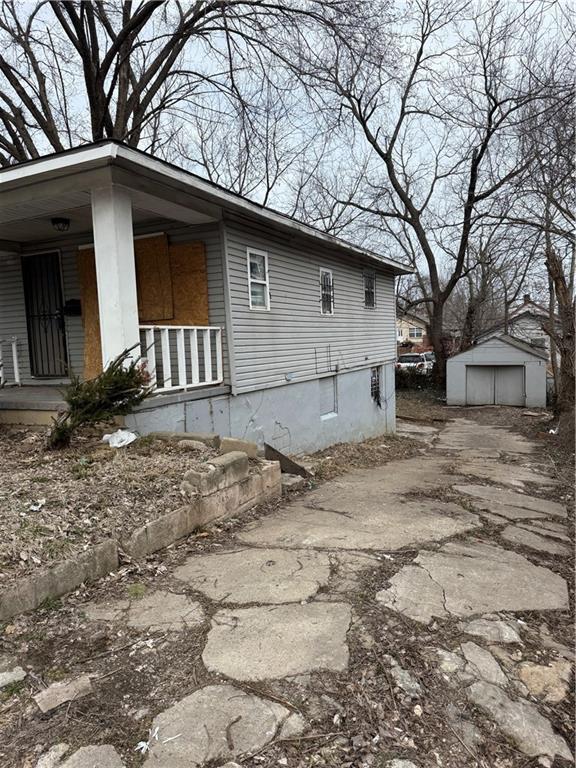 view of property exterior with an outbuilding, driveway, a porch, and a garage