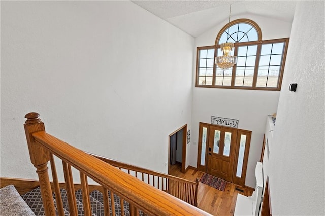 foyer featuring stairway, wood finished floors, lofted ceiling, and a chandelier