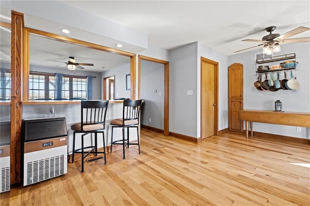 kitchen with a breakfast bar, baseboards, light wood finished floors, and ceiling fan