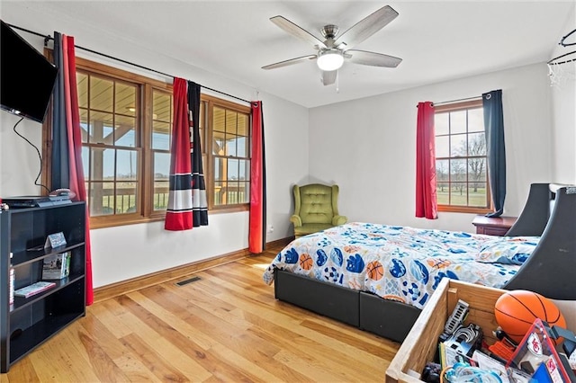 bedroom featuring ceiling fan, wood finished floors, visible vents, and baseboards