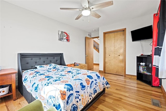 bedroom featuring wood finished floors, visible vents, a closet, and baseboards