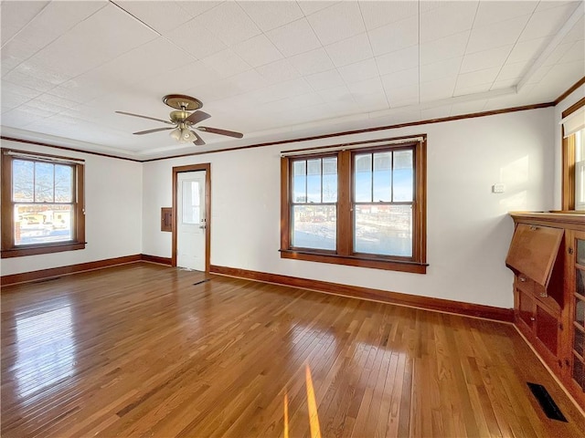 unfurnished living room featuring hardwood / wood-style flooring, baseboards, visible vents, and crown molding