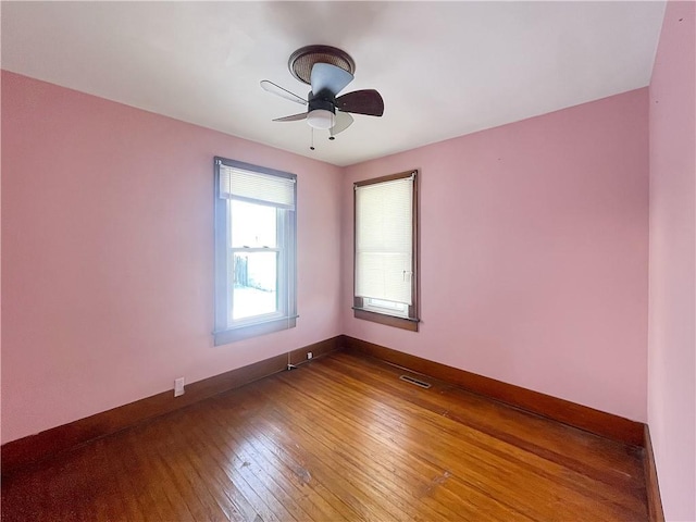 spare room featuring baseboards, visible vents, ceiling fan, and hardwood / wood-style floors