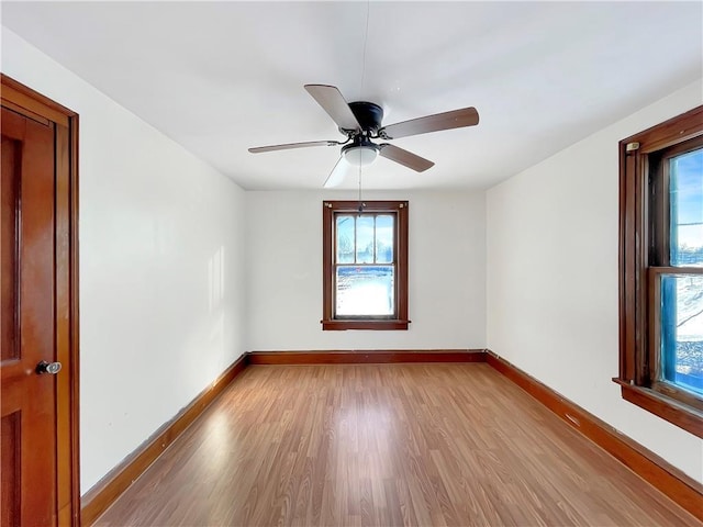 spare room featuring light wood-style floors, baseboards, and a ceiling fan