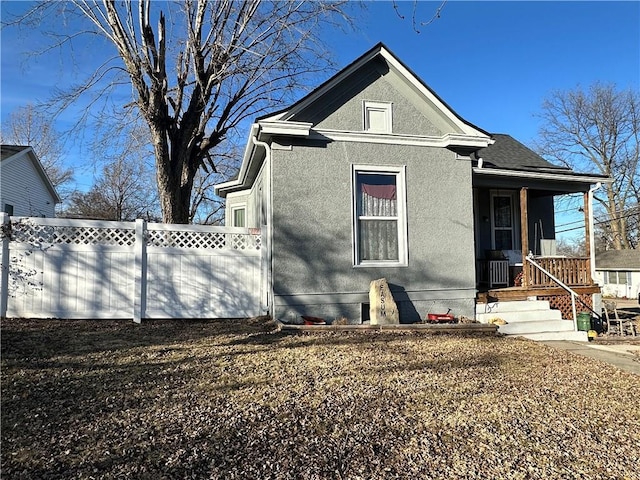 view of front of property with a shingled roof, fence, and stucco siding