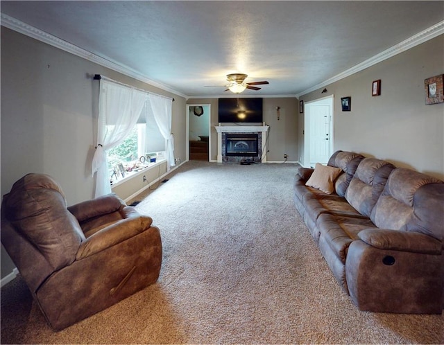 living room featuring a glass covered fireplace, carpet flooring, a ceiling fan, and crown molding