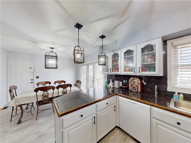 kitchen featuring glass insert cabinets, white cabinetry, white dishwasher, and a peninsula