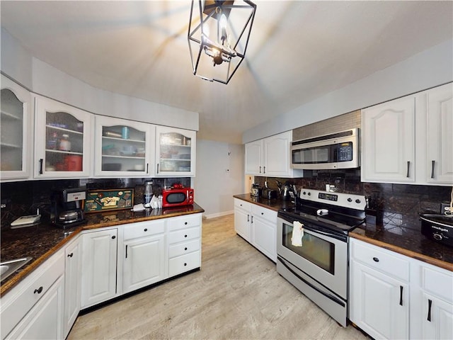 kitchen featuring light wood-type flooring, tasteful backsplash, appliances with stainless steel finishes, and white cabinets