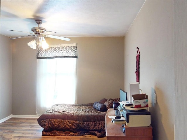 bedroom featuring ceiling fan, baseboards, and wood finished floors