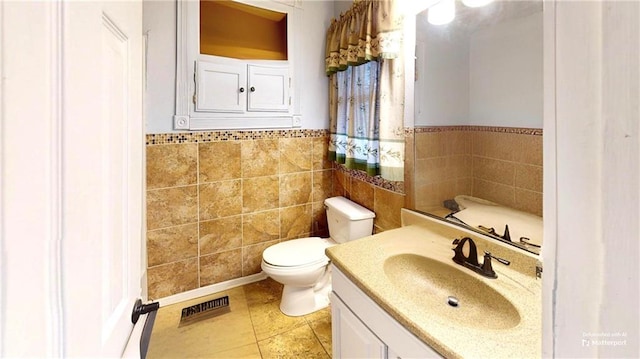 bathroom featuring visible vents, toilet, tile patterned floors, vanity, and tile walls