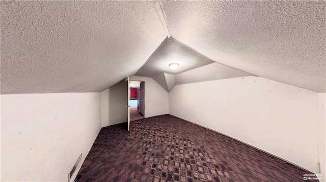 additional living space with vaulted ceiling, carpet floors, a textured ceiling, and visible vents