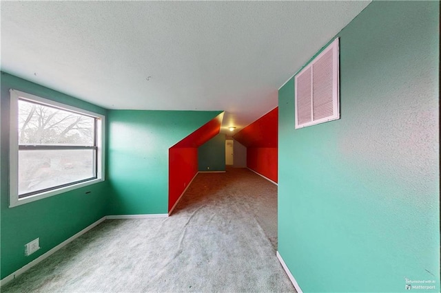 additional living space featuring lofted ceiling, baseboards, visible vents, and carpet flooring