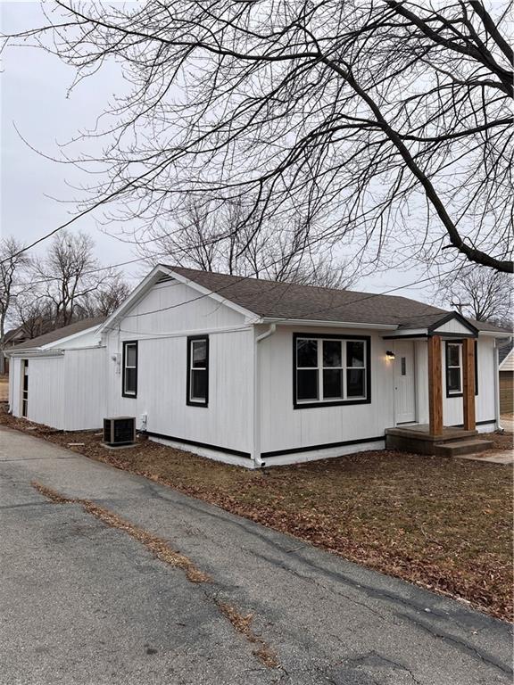 view of side of home with a shingled roof and central AC unit