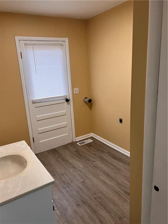 bathroom with visible vents, vanity, baseboards, and wood finished floors