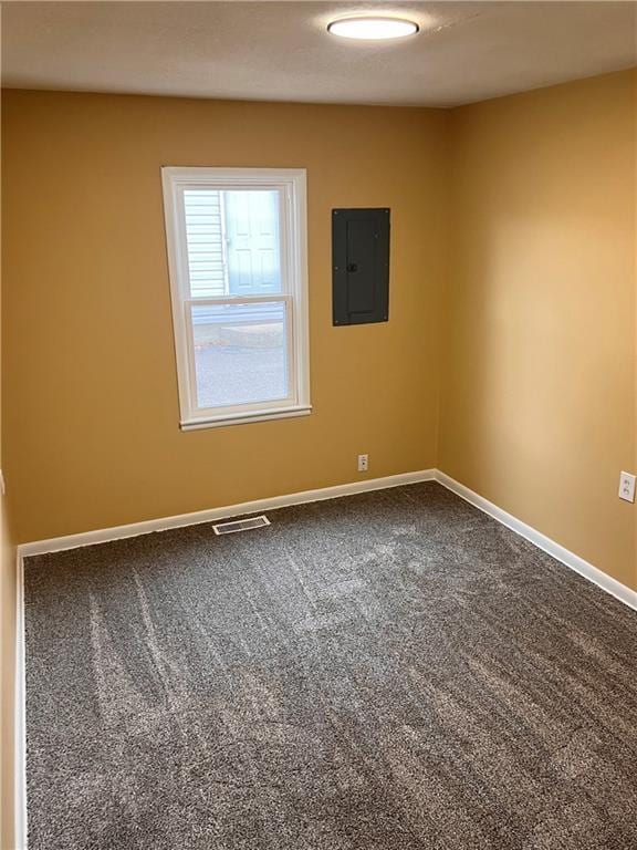 carpeted empty room featuring electric panel, visible vents, and baseboards