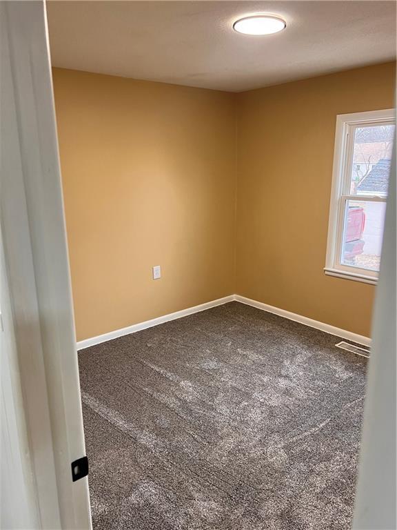 spare room with carpet, visible vents, and baseboards