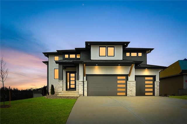 prairie-style house with stone siding, concrete driveway, a yard, and stucco siding