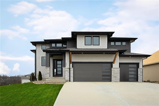 prairie-style home with an attached garage, concrete driveway, stone siding, stucco siding, and a front yard