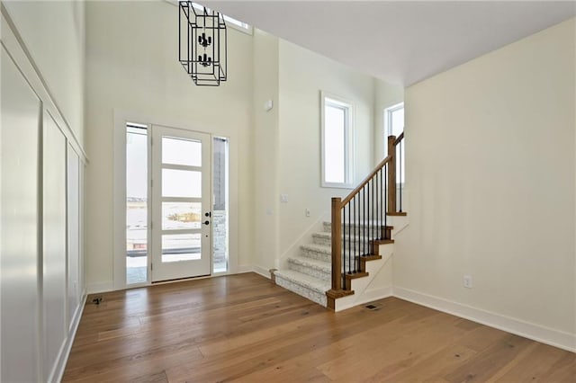 entryway featuring a towering ceiling, baseboards, stairway, and hardwood / wood-style floors