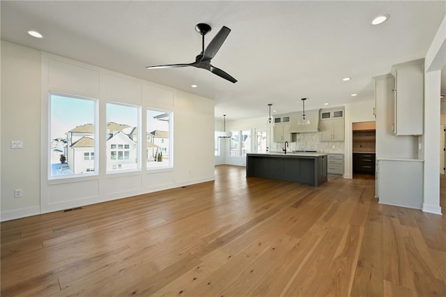unfurnished living room featuring ceiling fan, recessed lighting, a sink, wood finished floors, and visible vents