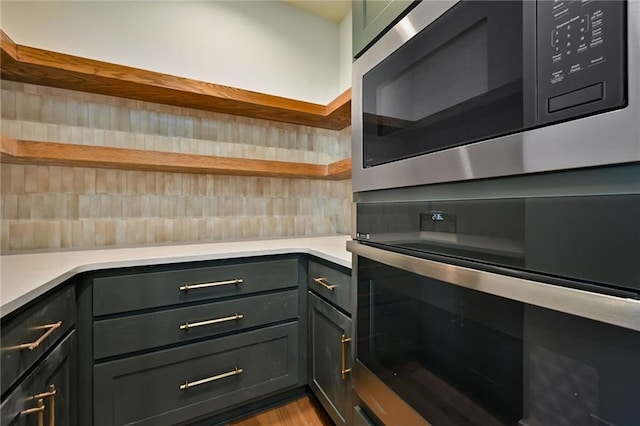 kitchen featuring light countertops, appliances with stainless steel finishes, open shelves, and decorative backsplash