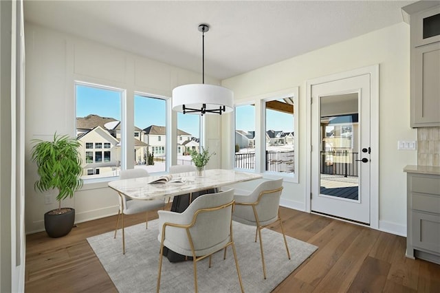 dining space featuring dark wood-type flooring, plenty of natural light, and baseboards