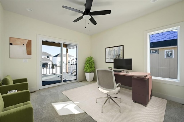 home office with a ceiling fan, light carpet, and baseboards