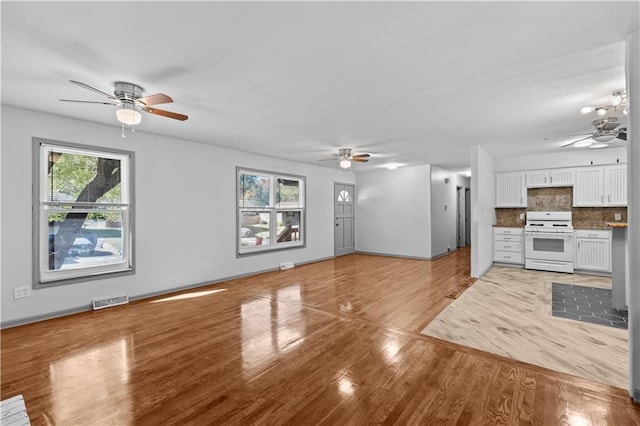 unfurnished living room with light wood finished floors, baseboards, visible vents, and a ceiling fan