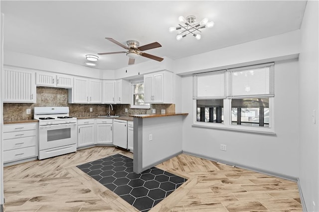 kitchen featuring dark countertops, decorative backsplash, white cabinetry, a sink, and white appliances