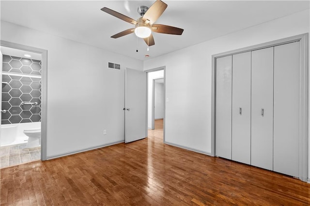 unfurnished bedroom featuring visible vents, a ceiling fan, a closet, hardwood / wood-style floors, and ensuite bath