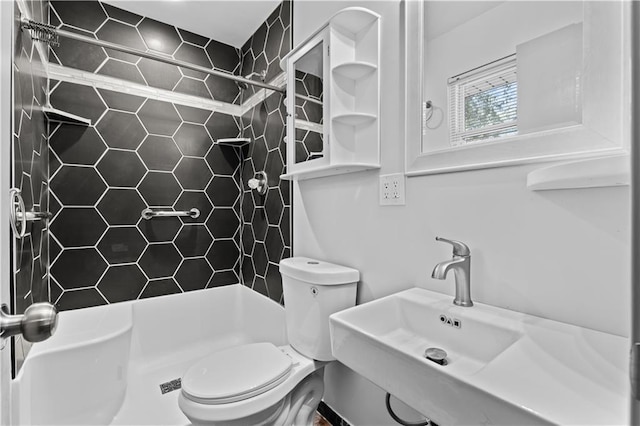 bathroom with a sink, a tile shower, and toilet