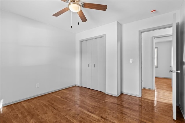 unfurnished bedroom featuring a closet, wood finished floors, a ceiling fan, and baseboards