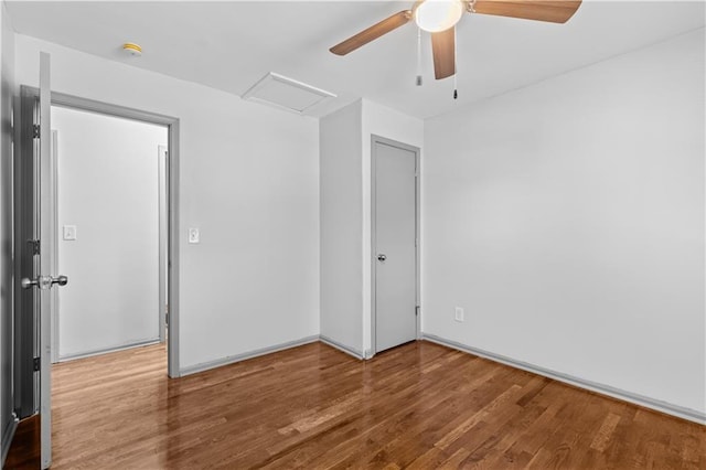 unfurnished bedroom featuring attic access, a ceiling fan, and wood finished floors