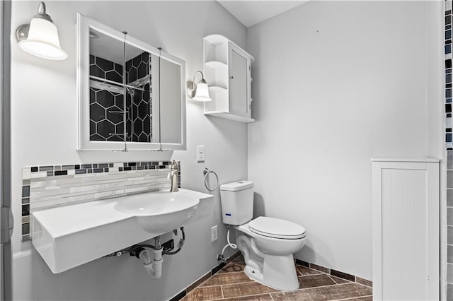 bathroom with baseboards, toilet, and decorative backsplash