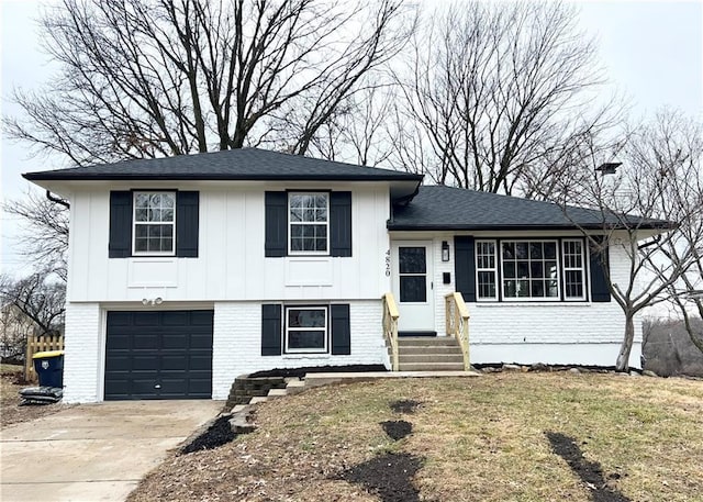 tri-level home featuring a garage, concrete driveway, board and batten siding, and brick siding