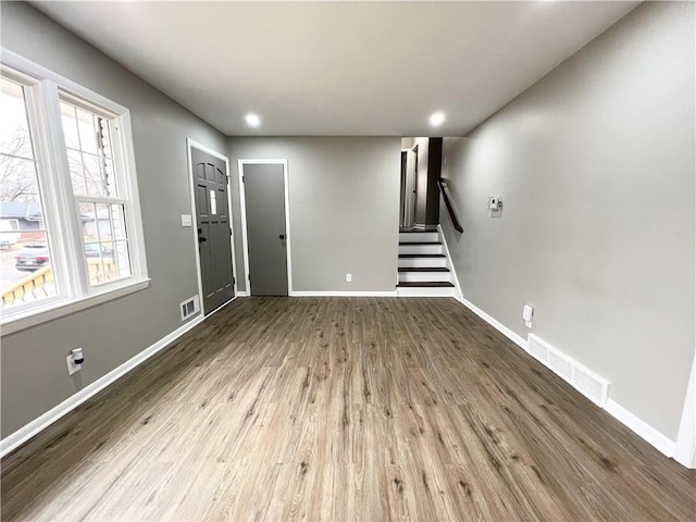 entryway featuring wood finished floors, visible vents, baseboards, and stairs