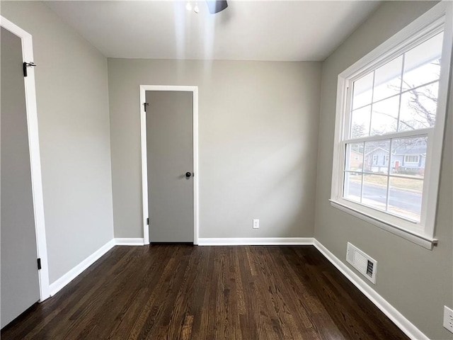 spare room with baseboards, visible vents, and dark wood finished floors