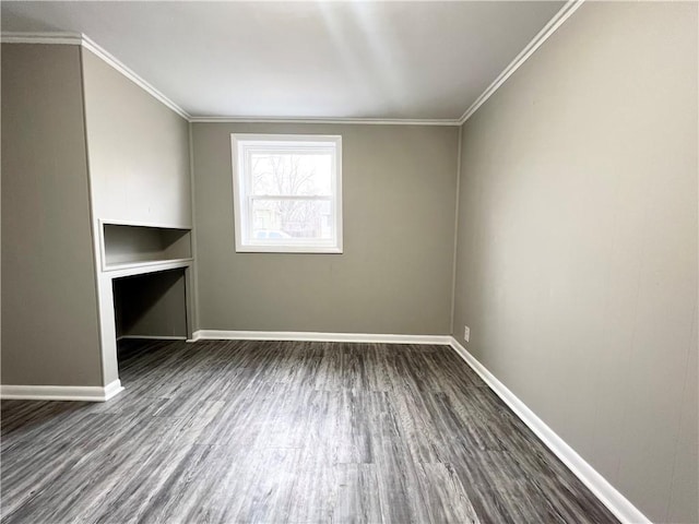 spare room featuring dark wood-style flooring, crown molding, and baseboards