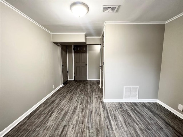 empty room featuring dark wood-style floors, visible vents, and ornamental molding