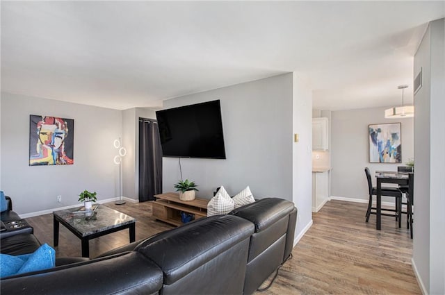 living room with visible vents, baseboards, and wood finished floors