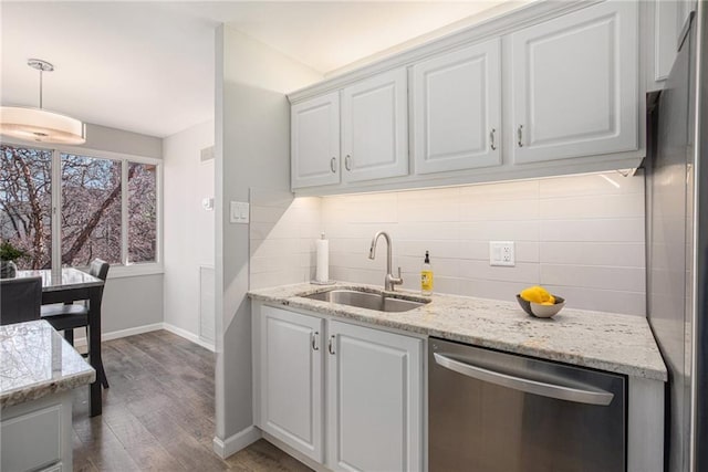 kitchen with appliances with stainless steel finishes, dark wood-style flooring, a sink, white cabinetry, and backsplash